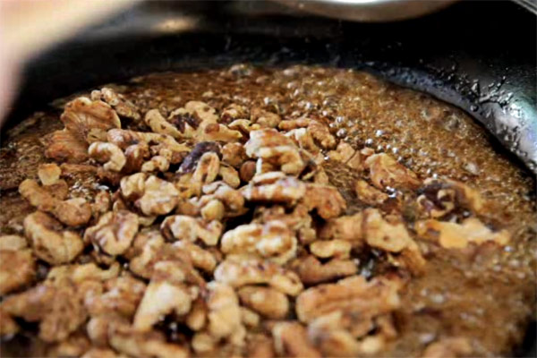 Add the toasted walnuts to the syrup mixture. Turn the heat up a bit if the syrup stops bubbling. Cook for 1 - 2 minutes until the syrup has thickened and the walnuts are well coated.